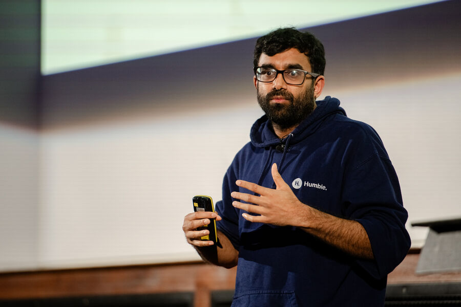 Mahdi Shariff on stage in a Humble hoodie, holding a clicker