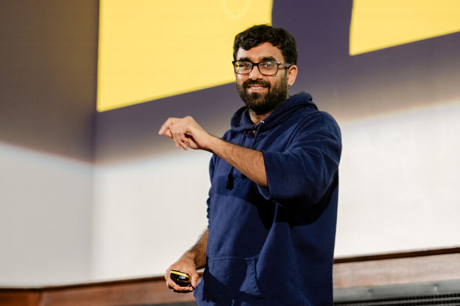 Mahdi Shariff on stage in a Humble hoodie, pointing to a slide