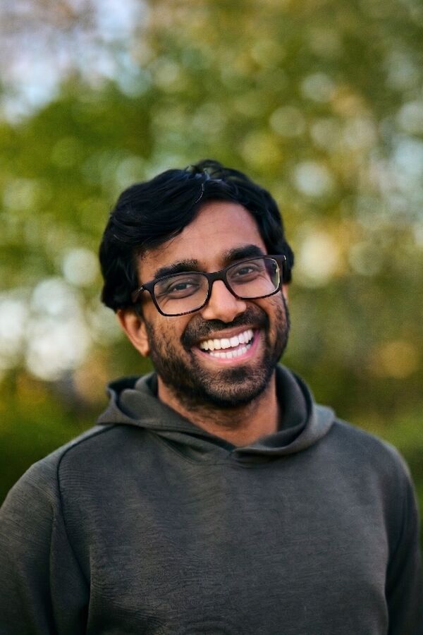 Mahdi Shariff smiling, outdoors, in a green hoodie